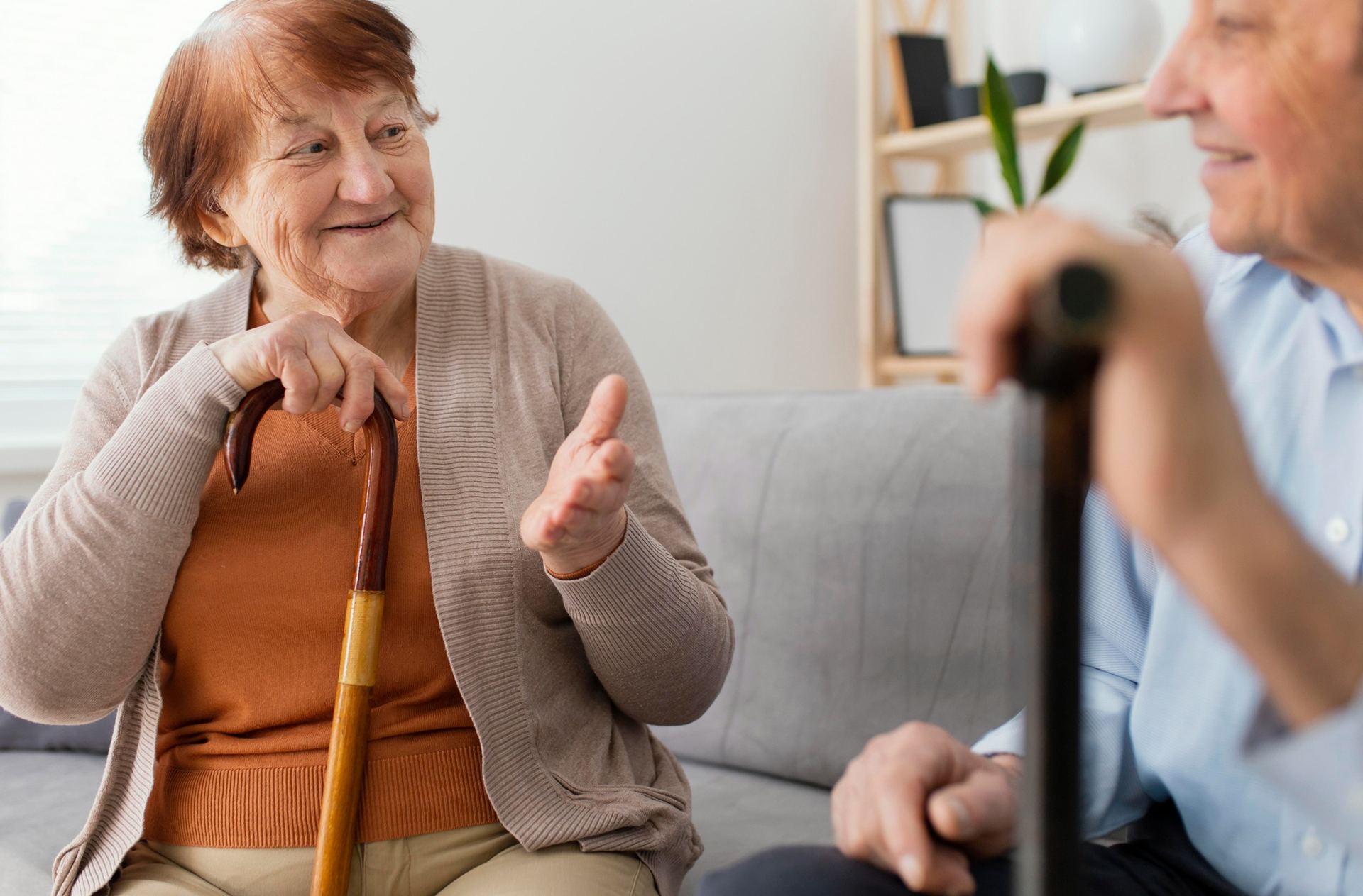 Uśmiechnięta seniorka z laską rozmawia z seniorem podczas codziennego dnia w Domu Seniora Kalina w Gdańsku