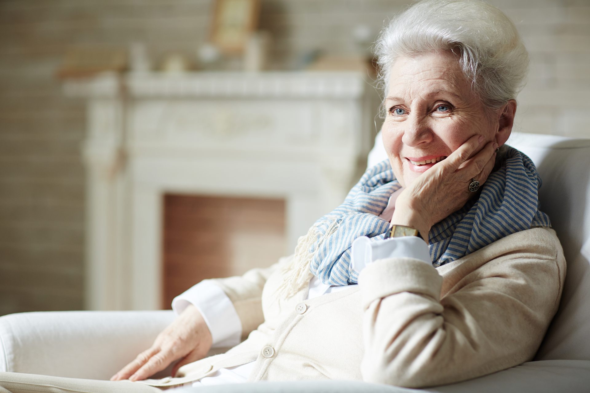 Uśmiechnięta seniorka w fotelu przy kominku, mieszkanka Domu Seniora Kalina w Gdańsku