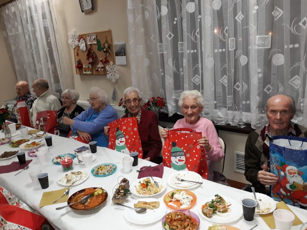 Seniorzy z prezentami przy świątecznym stole podczas wigilii w Domu Seniora Kalina w Gdańsku